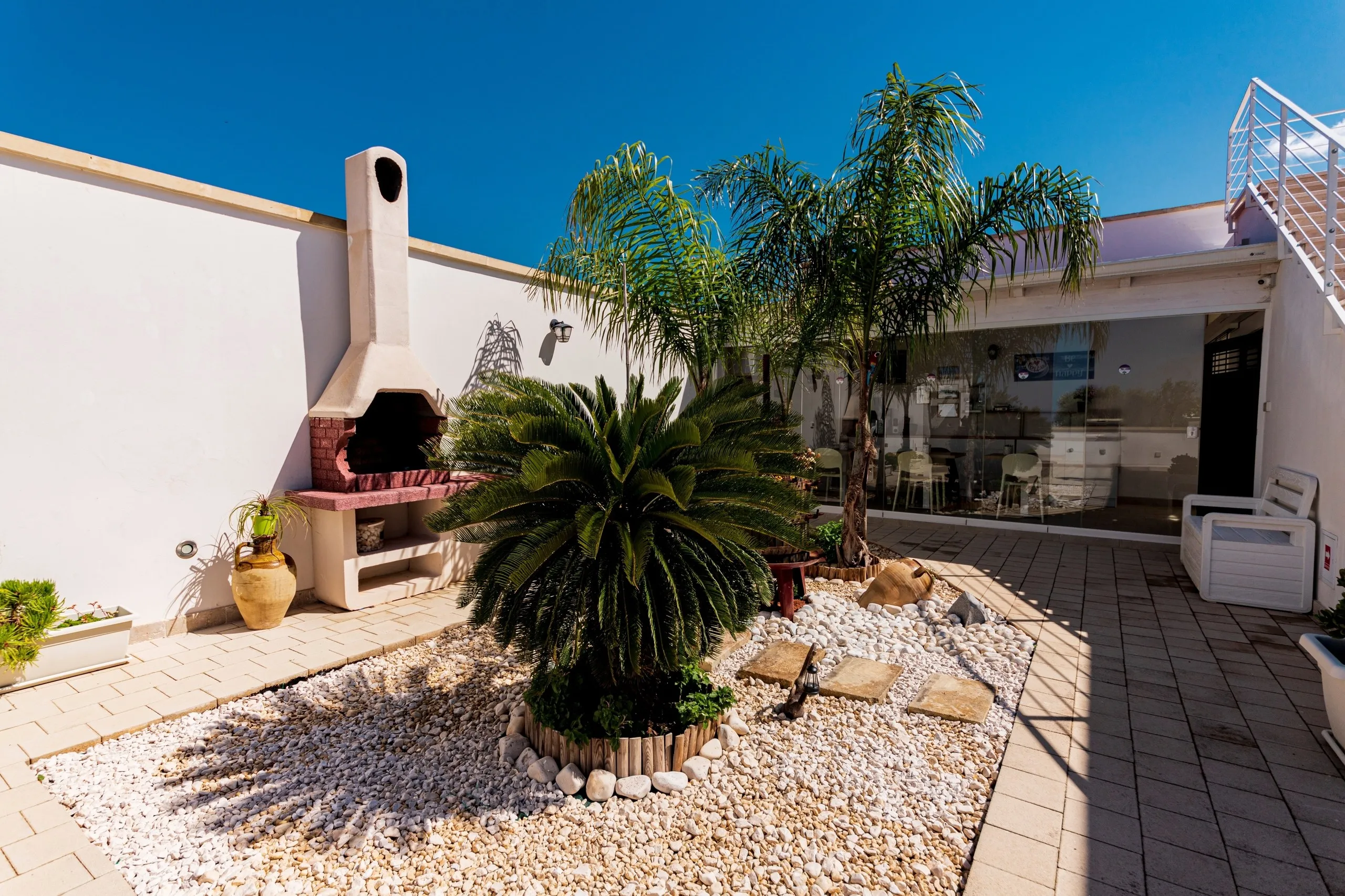 Le barbecue et le palmier dans la cour de Villa Noemi