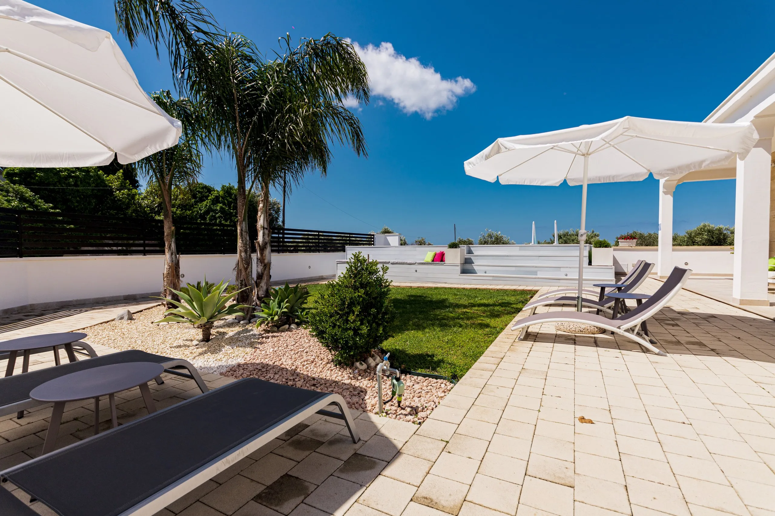 Le solarium de Villa Noemi, avec les parasols et les transats donnant sur le jardin